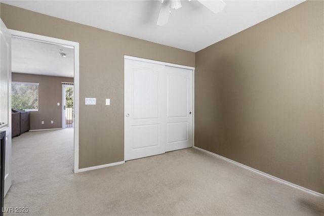 unfurnished bedroom with baseboards, a closet, ceiling fan, and light colored carpet