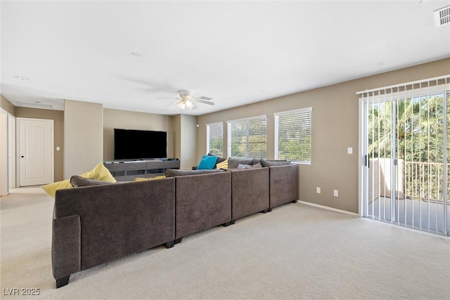 living area with a wealth of natural light, light carpet, baseboards, and ceiling fan
