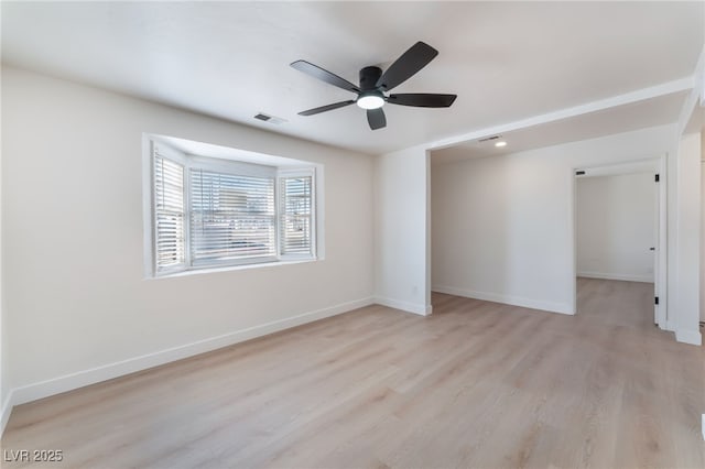 empty room with light wood finished floors, baseboards, ceiling fan, and visible vents