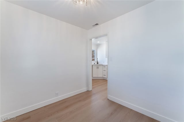 unfurnished room with baseboards, light wood-type flooring, and visible vents