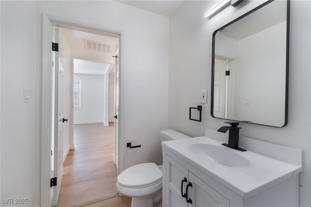 bathroom with toilet, vanity, visible vents, and wood finished floors