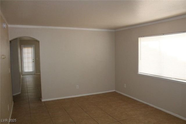 tiled spare room with arched walkways, ornamental molding, and baseboards