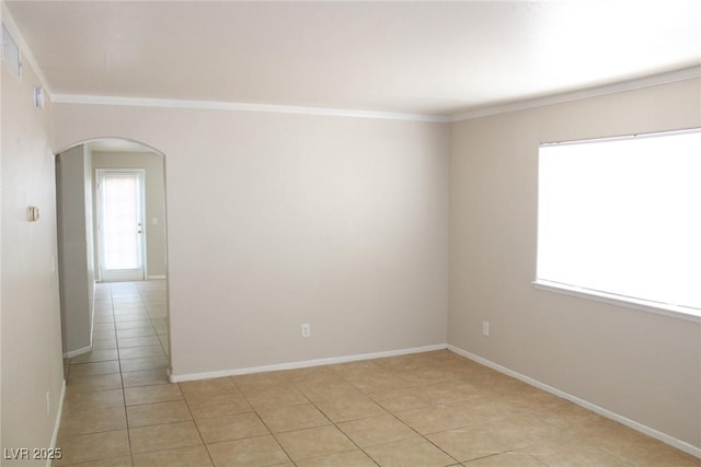 empty room with arched walkways, light tile patterned flooring, ornamental molding, and baseboards