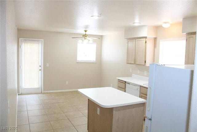 kitchen featuring white appliances, light brown cabinets, ceiling fan, light countertops, and a center island