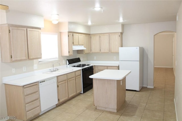 kitchen featuring white appliances, light brown cabinets, under cabinet range hood, and a sink