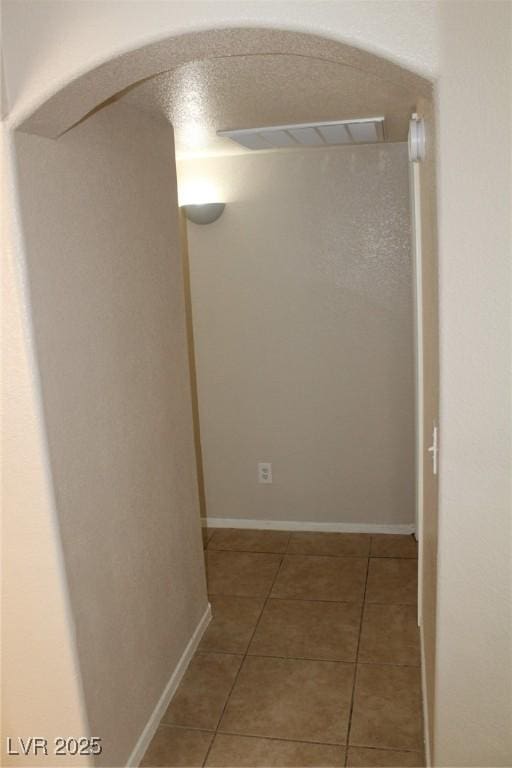 hall with arched walkways and tile patterned flooring