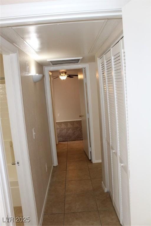 hall featuring baseboards and light tile patterned floors