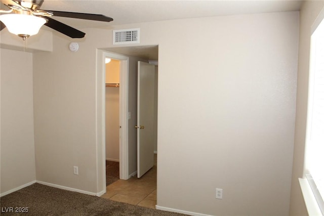 unfurnished bedroom featuring a spacious closet, light tile patterned flooring, a closet, baseboards, and ceiling fan