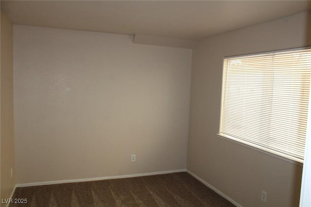 spare room with dark carpet and baseboards