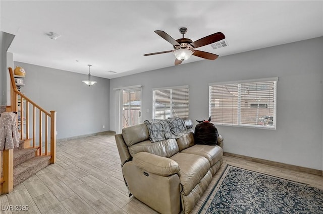 living area with light wood-style flooring, ceiling fan, stairs, and baseboards