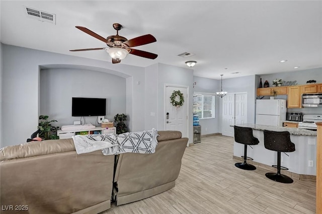living area with a ceiling fan, a chandelier, light wood finished floors, baseboards, and recessed lighting