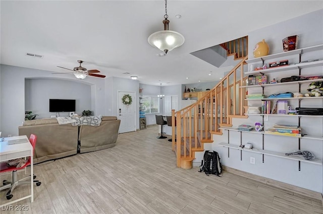 living room with stairway, a ceiling fan, and wood finished floors