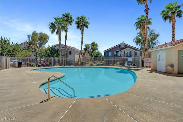 community pool featuring a patio area, fence, and a residential view