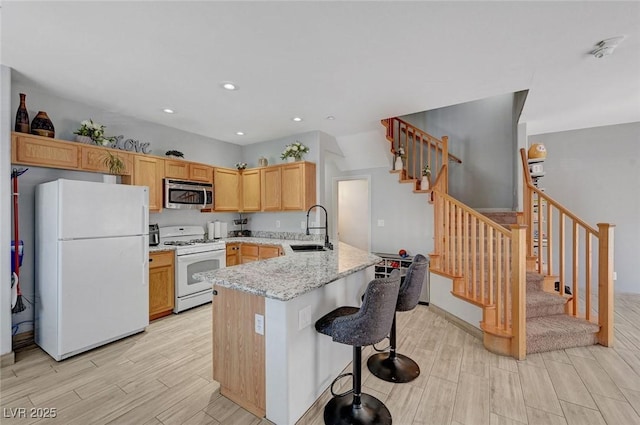 kitchen featuring white appliances, a sink, wood tiled floors, a peninsula, and recessed lighting