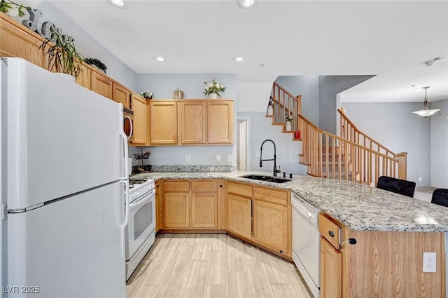 kitchen featuring white appliances, a sink, a peninsula, light brown cabinets, and light stone countertops