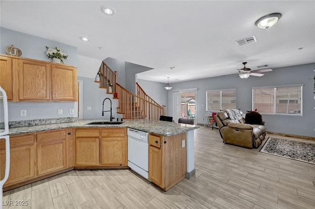 kitchen featuring white dishwasher, a sink, a ceiling fan, a peninsula, and light wood-style flooring