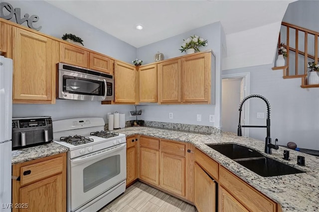 kitchen with white appliances, a sink, light stone countertops, and light brown cabinetry
