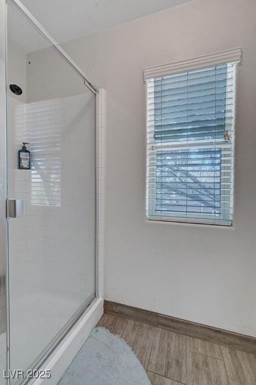 bathroom with wood finished floors, a shower stall, and baseboards