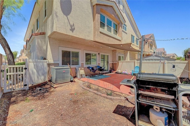 rear view of property with stucco siding, central AC, a fenced backyard, and a patio