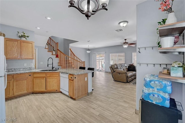 kitchen with white appliances, a sink, a peninsula, ceiling fan, and a chandelier