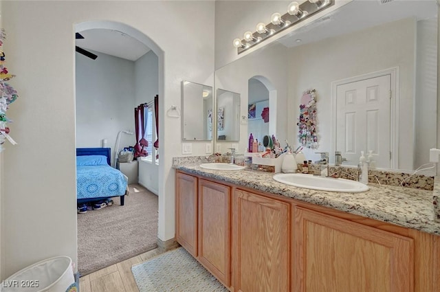 bathroom featuring wood finished floors, double vanity, and ensuite bath
