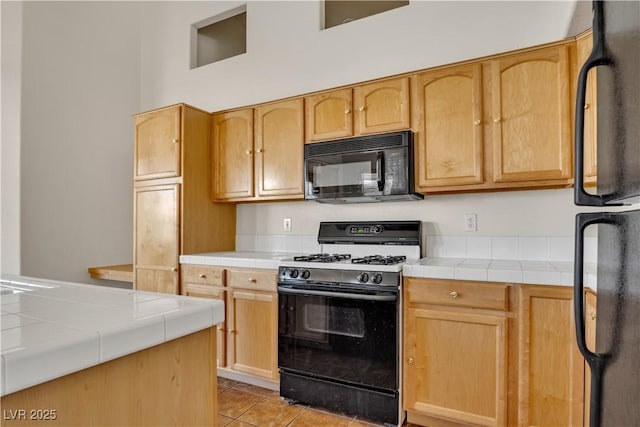8940 Emery Lake St, Las Vegas, NV 89123 - kitchen with black appliances, tile counters, light brown cabinets, and light tile patterned floors