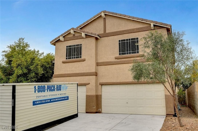 view of front of property with concrete driveway, stucco siding, an attached garage, and fence
