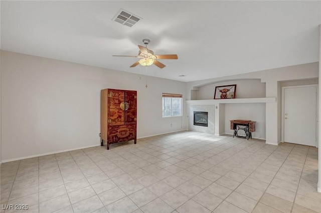 unfurnished living room with a ceiling fan, a tile fireplace, light tile patterned flooring, and baseboards
