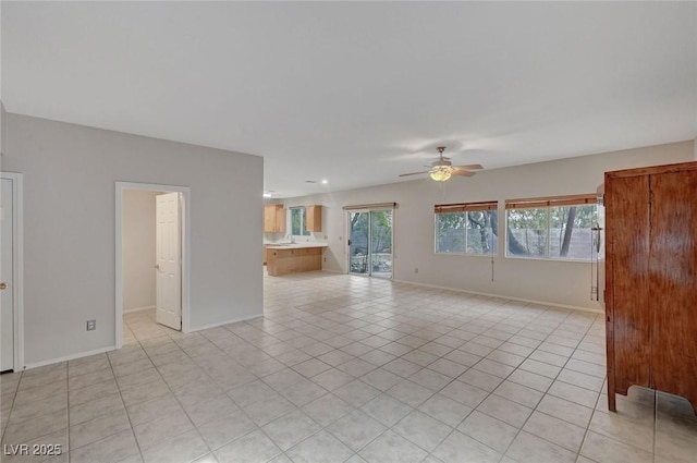 unfurnished living room featuring ceiling fan, light tile patterned floors, and baseboards
