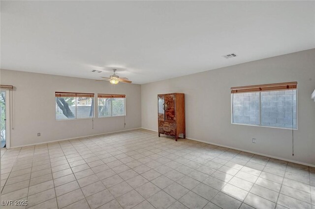 unfurnished room featuring ceiling fan, light tile patterned floors, and baseboards
