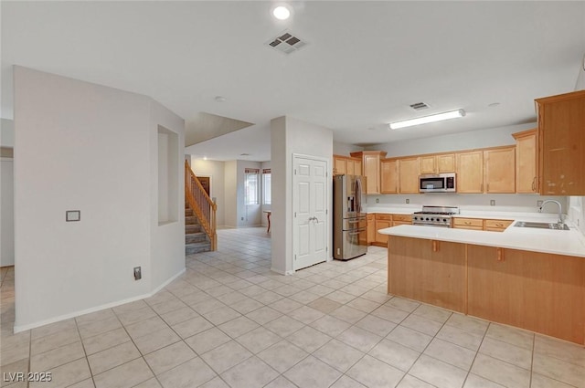 kitchen with appliances with stainless steel finishes, a sink, light countertops, and a peninsula