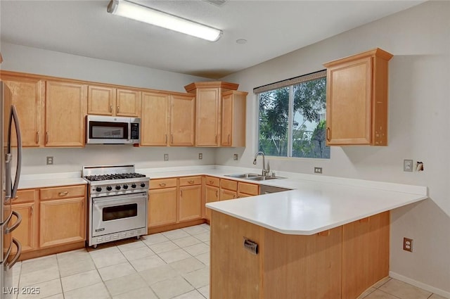 kitchen with stainless steel appliances, a sink, a peninsula, light brown cabinets, and light countertops