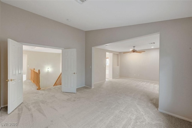spare room with light colored carpet, baseboards, and a ceiling fan