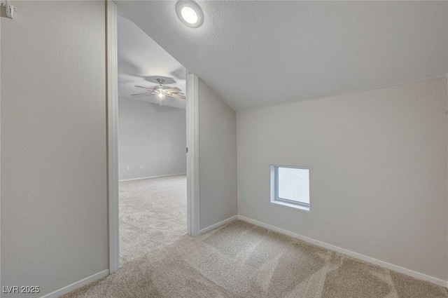 unfurnished room featuring carpet flooring, ceiling fan, vaulted ceiling, and baseboards