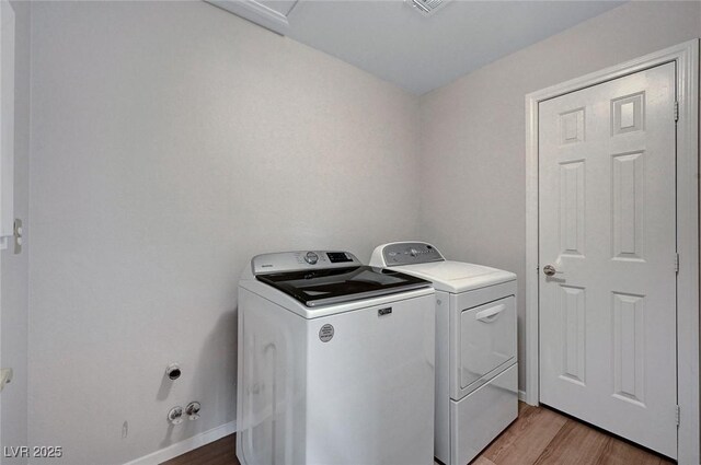 laundry room featuring washer and clothes dryer and light wood-type flooring