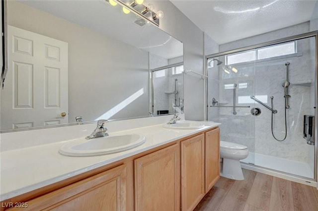 full bathroom with toilet, double vanity, wood finished floors, and a stall shower