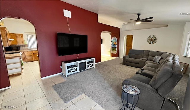 living room featuring light tile patterned floors, a healthy amount of sunlight, visible vents, ceiling fan, and arched walkways