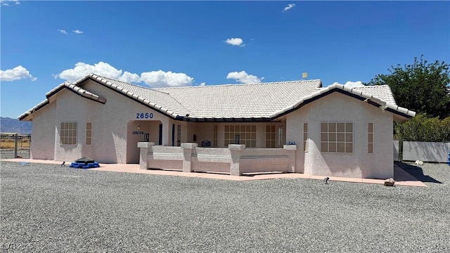 view of front of house featuring stucco siding, a tile roof, and fence