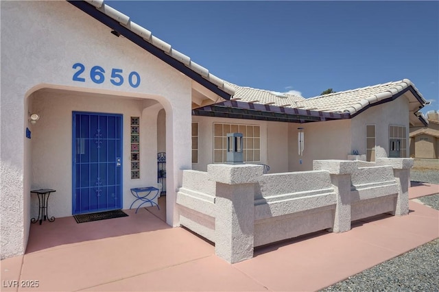 property entrance with stucco siding and a tiled roof