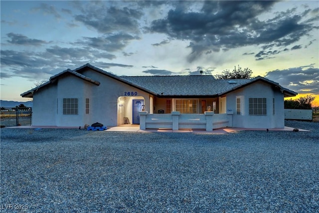 back of house at dusk featuring stucco siding