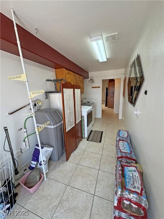 kitchen with light tile patterned floors, range, visible vents, and a textured ceiling