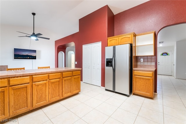 2650 Sagebrush Ave, Pahrump, NV 89048 - kitchen featuring stainless steel fridge, arched walkways, high vaulted ceiling, a ceiling fan, and tile countertops