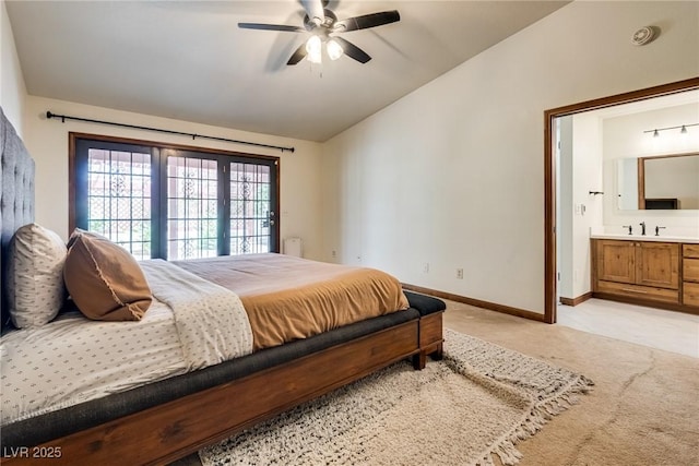 5242 Dickens Dr, Las Vegas, NV 89119 - bedroom featuring connected bathroom, a sink, light carpet, baseboards, and vaulted ceiling