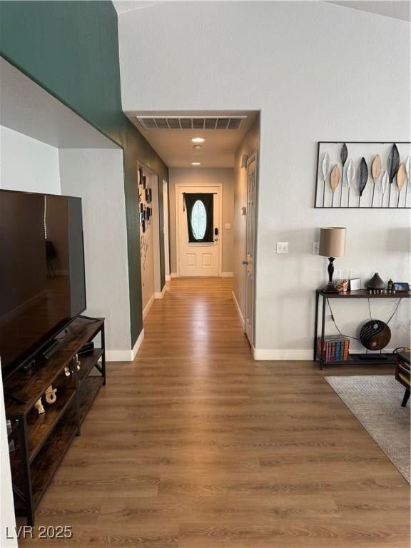 corridor featuring wood finished floors, visible vents, and baseboards