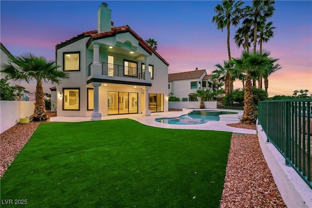 2589 Sun Reef Rd, Las Vegas, NV 89128 - back of property at dusk with a balcony, stucco siding, a fenced backyard, and a chimney