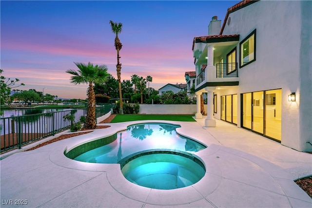 2589 Sun Reef Rd, Las Vegas, NV 89128 - pool at dusk featuring a fenced backyard, a patio area, a water view, and a pool with connected hot tub