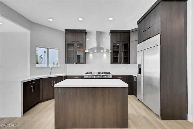 2589 Sun Reef Rd, Las Vegas, NV 89128 - kitchen with wall chimney range hood, stainless steel appliances, light countertops, light wood-type flooring, and glass insert cabinets