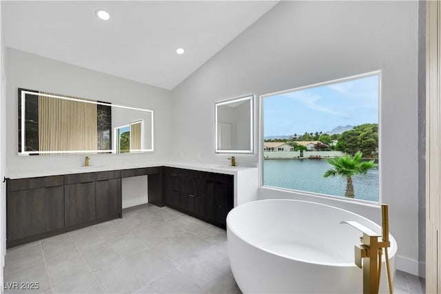 2589 Sun Reef Rd, Las Vegas, NV 89128 - bathroom featuring lofted ceiling, double vanity, a freestanding tub, healthy amount of natural light, and recessed lighting