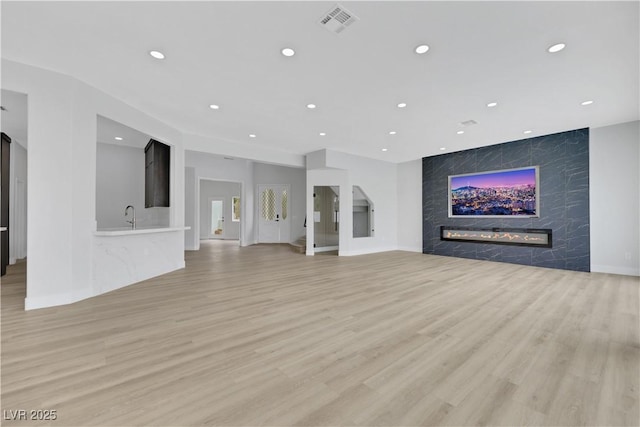 2589 Sun Reef Rd, Las Vegas, NV 89128 - unfurnished living room with a fireplace, light wood-style flooring, and recessed lighting
