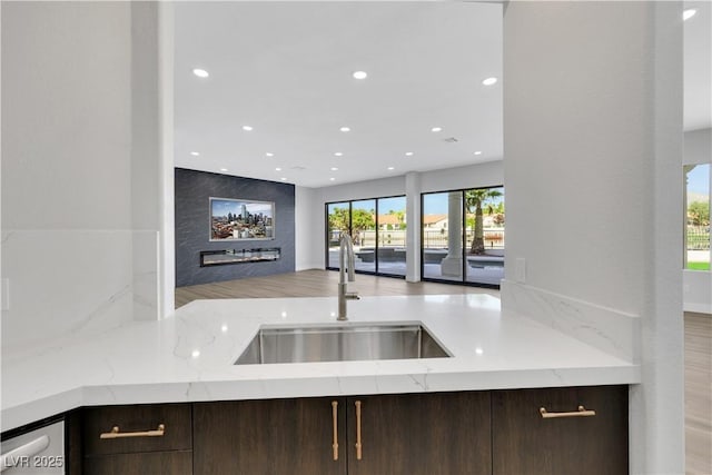 2589 Sun Reef Rd, Las Vegas, NV 89128 - kitchen featuring dark brown cabinetry, recessed lighting, light stone counters, and a fireplace